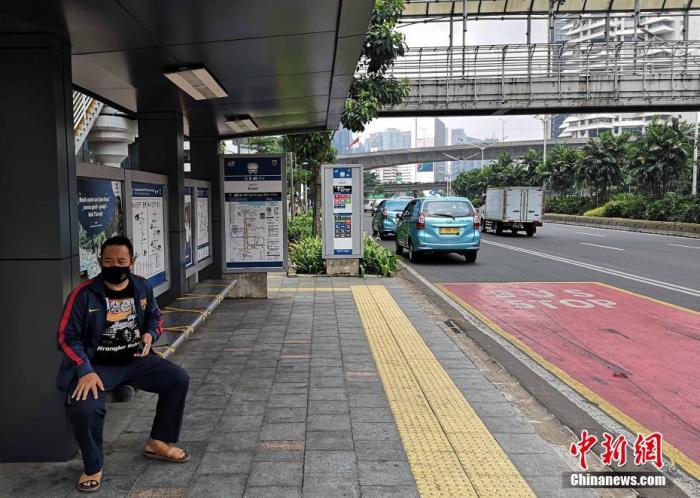 资料图：图为一印尼市民佩戴口罩在公交停靠站候车。
记者 林永传 摄